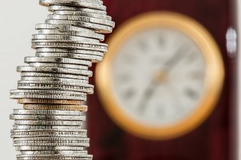 Hromada mincí a hodiny v pozadí Hromada mincí a hodiny v pozadí