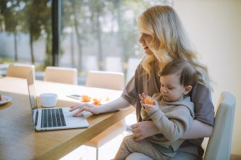 Matka s dítětem na klíně, pracující na laptopu [fotografka Anastasia Shuraeva]